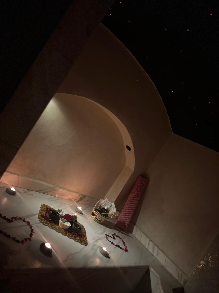 Alcôve hammam de luxe, marbre, pétales de rose en cœurs, bougies et plafond étoilé.