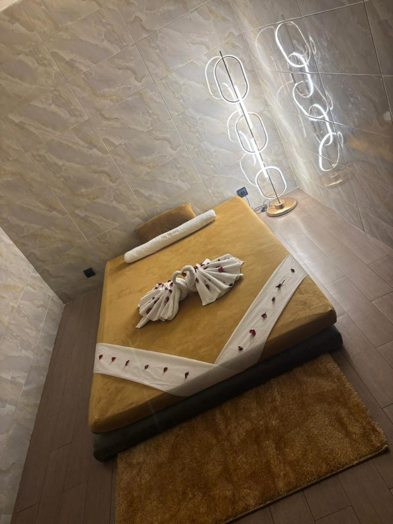 Lit de massage, draps dorés, serviettes en forme de cygnes, pétales de rose et murs en marbre.
