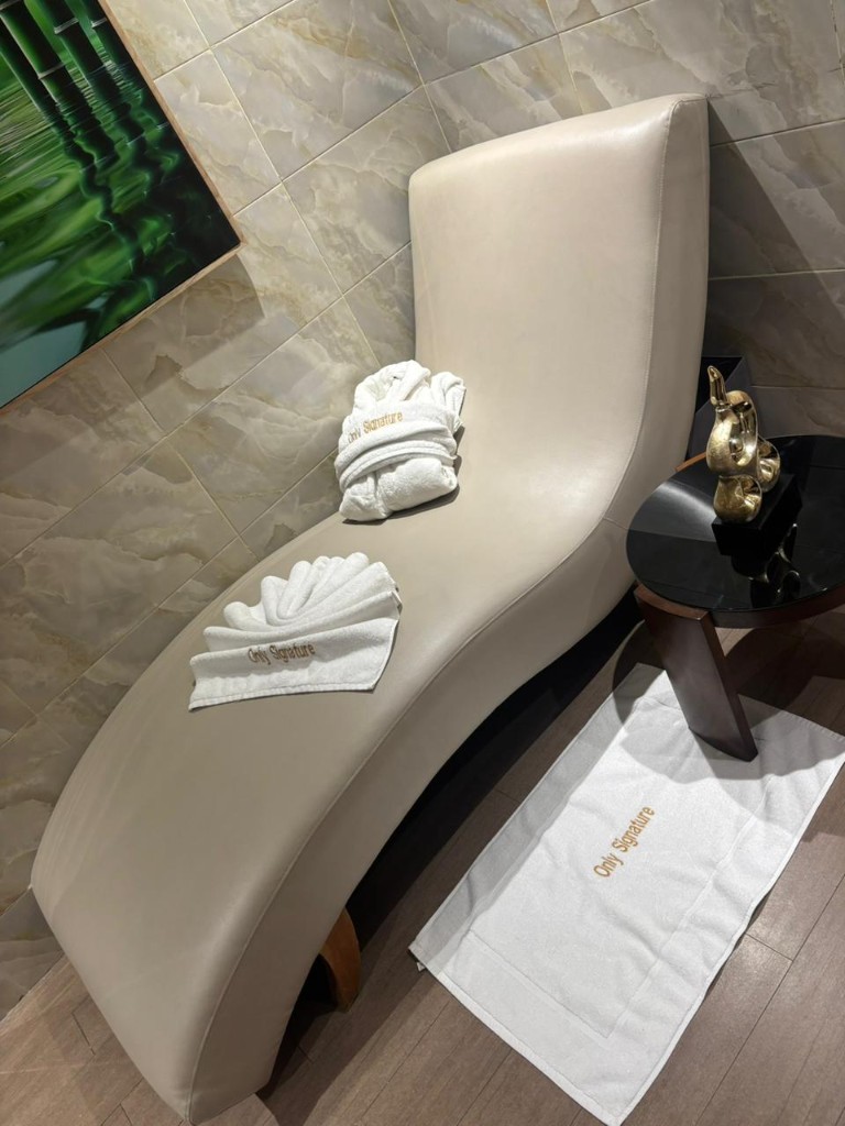 Chaise longue moderne avec peignoir et serviettes Only Signature, murs en marbre.