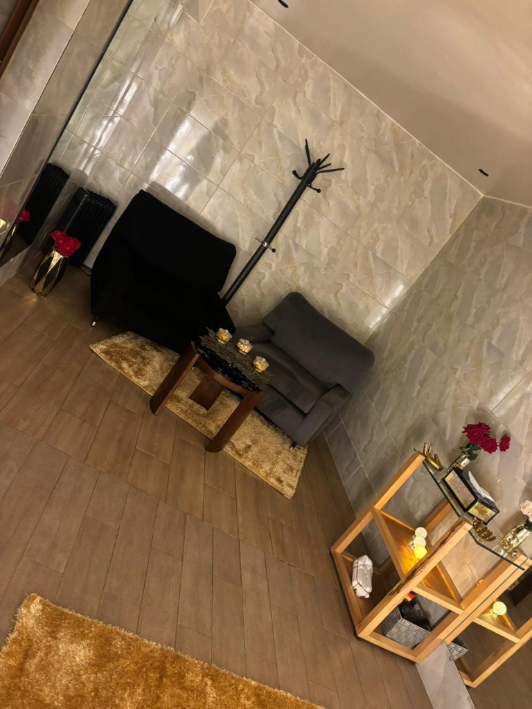 Salon d'accueil du spa avec fauteuils, roses, murs en marbre et tapis doré.